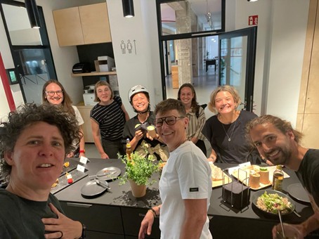 Projektteam steht um einen Tisch mit Pflanzen, Tellern und Getränken in einem modernen Innenraum